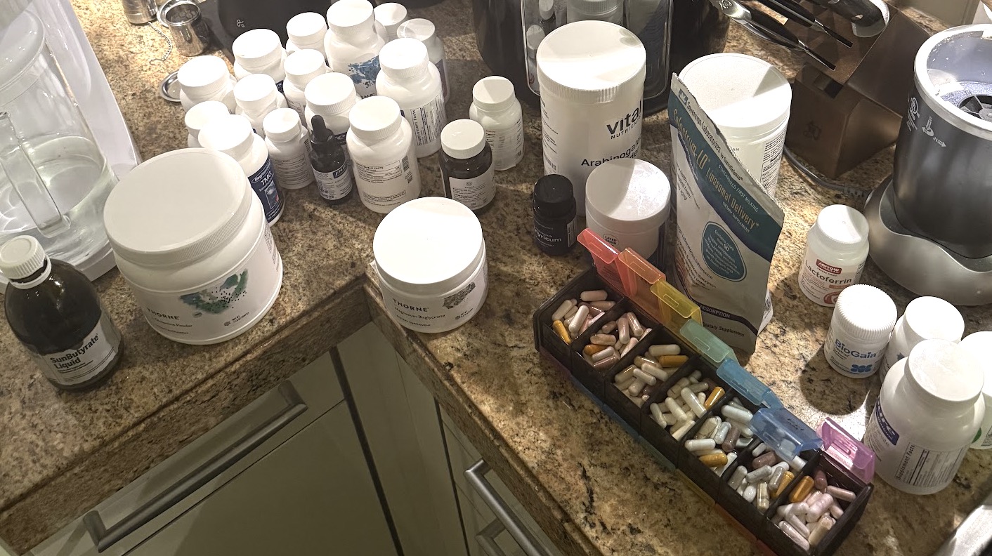 Nick's kitchen counter covered in supplement bottles and a weekly pill organizer